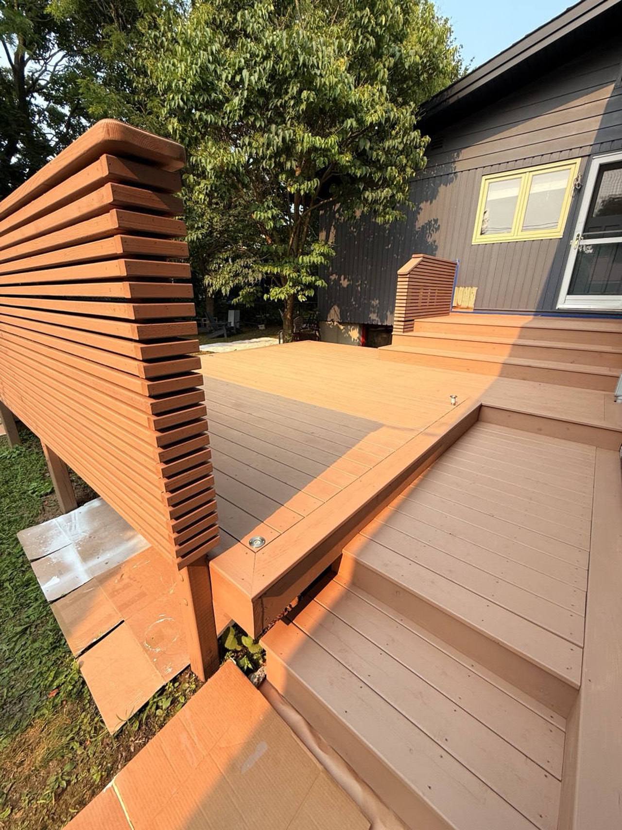 Completed deck renovation with warm freshly stained boards and matching railing, finished on a sunny day.