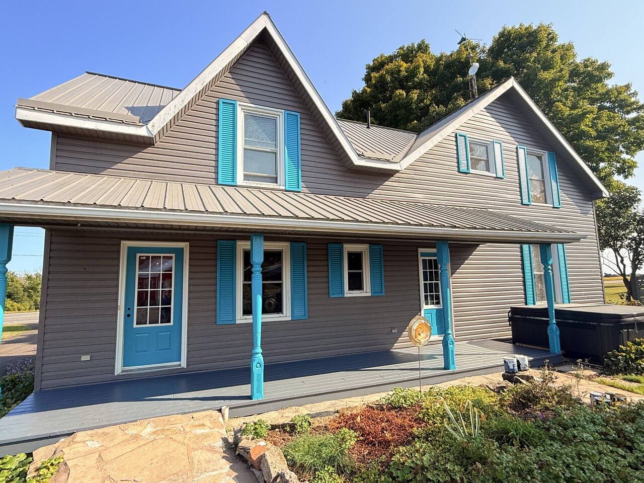 Grey home with white trim, blue shutters and a blue front door after a full exterior repaint in Eastern Ontario