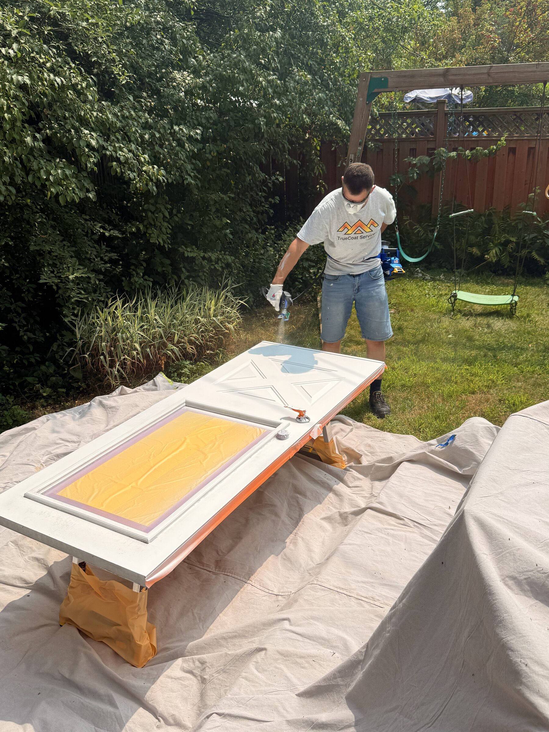 Exterior door being spray-painted in a Rockcliffe Park backyard